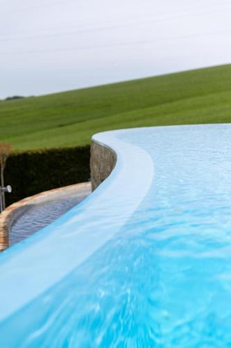 a swimming pool with blue water next to a field at B&B Casa Fanny Riviera Del Conero in Loreto