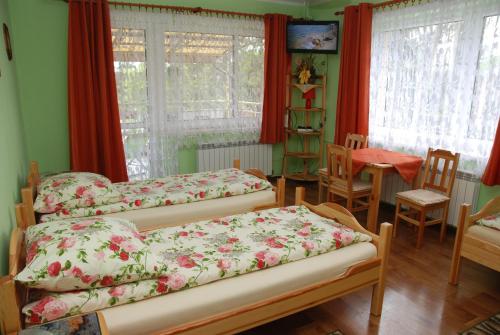 - une chambre avec 3 lits, une table et des fenêtres dans l'établissement Noclegi nad Leśniówką, à Żarki