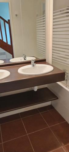 uma casa de banho com 2 lavatórios e um espelho grande em SABLES D'OR em Frehel