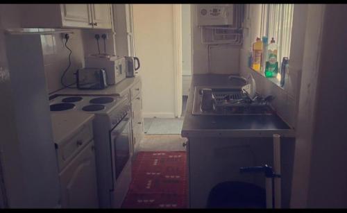 uma pequena cozinha com um fogão e um lavatório em Cosy stay em Birmingham