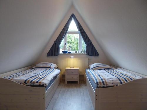 deux lits dans une chambre mansardée avec une fenêtre dans l'établissement Haus Pier 24 An der Rennweide 24a 96qm, à Dangast