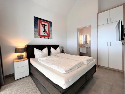 een slaapkamer met een groot bed met witte lakens bij Loft Sonne & Mehr, Am Alten Deich 26 10 in Dangast