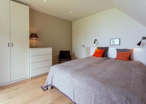 - une chambre avec un grand lit et deux oreillers orange dans l'établissement Haus Dangaster Gezeiten, An der Rennweide 32, 120qm, à Varel
