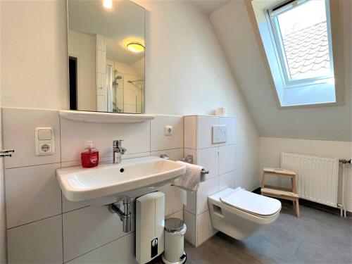 a white bathroom with a sink and a toilet at Haus Strandkieker, An der Rennweide 12c, 65qm in Dangast