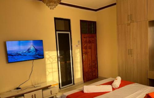 Cherry home في مومباسا: غرفة نوم مع تلفزيون على الحائط وسرير