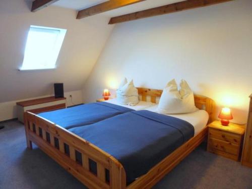 une chambre avec un grand lit en bois avec des draps bleus dans l'établissement Haus Seemöwe Hollwert 33d 90qm, à Dangast
