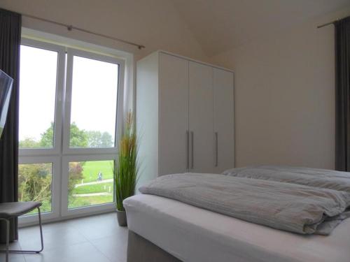 um quarto com uma cama grande e uma janela grande em Premium-Penthouse Oceans Eleven, Am Alten Deich 14 11 em Dangast