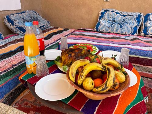 a table with a bowl of bananas and fruit on a bed at MAISON D'HOTE DAR IMRANE in Tatta