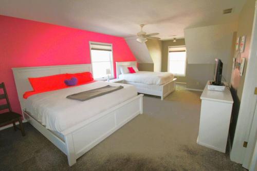 a bedroom with two beds and a red wall at Hummingbird Hideaway in Branson