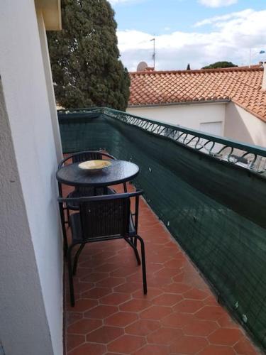 une table et une chaise assises sur un balcon dans l'établissement Appartement tout confort d'une villa, à Canet