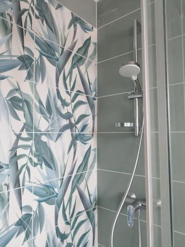 une salle de bain avec une douche avec un rideau de douche à feuilles dans l'établissement Appartement tout confort d'une villa, à Canet