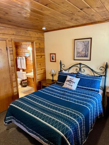 a bedroom with a bed with a blue comforter at Andruss Motel in Walker