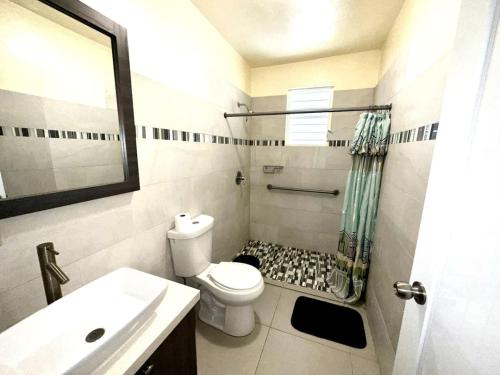 een witte badkamer met een toilet en een wastafel bij Sandy Shores Retreat Beach Apt in Cabo Rojo in Boqueron