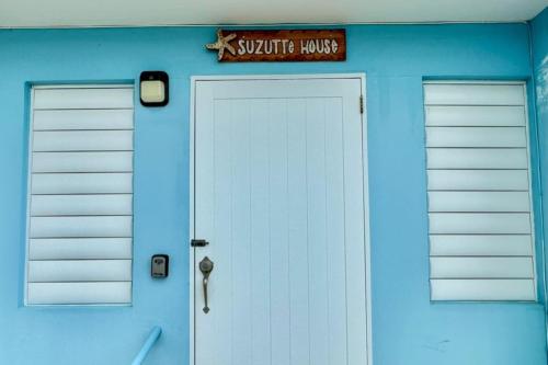 uma garagem azul com uma porta branca e um sinal nela em Tropical Escape Apt at Combate Beach em Boqueron