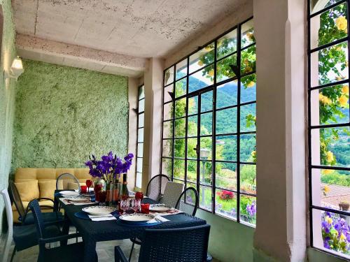 comedor con mesa, sillas y ventanas en Villa Oleandra nearby Argegno with privet Garden & Pool, en Dizzasco