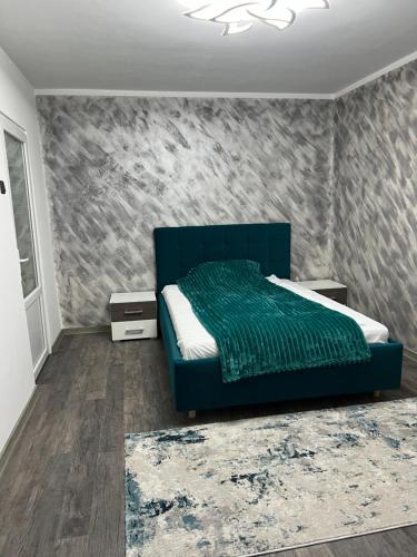 a bedroom with a blue bed and a wall at Green Apartament in Târgu Jiu