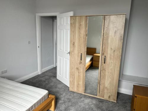 a bedroom with a wooden cabinet with a bed at Nice 2Bedroom house for Family in Nottingham