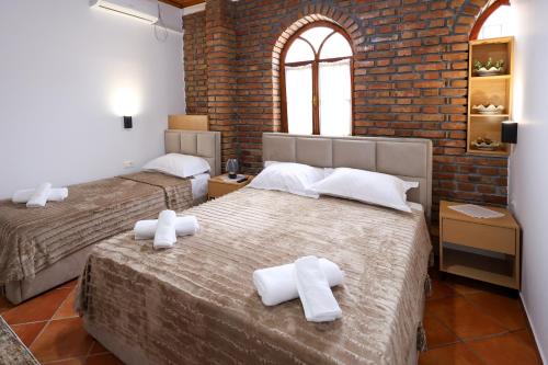 a bedroom with two beds and a brick wall at Hotel Boutique BUZI in Berat