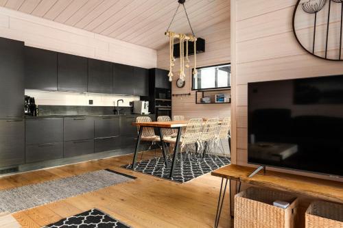 a kitchen with black cabinets and a table with chairs at Villa Ritva - Modern - Lakefront - Hot Tub in Hyvinkää