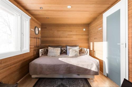 Cama en habitación con paredes de madera y ventana en Villa Ritva - Modern - Lakefront - Hot Tub en Hyvinkää