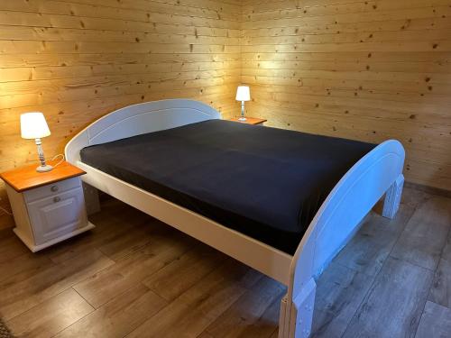 ein großes Bett in einem Holzzimmer mit zwei Lampen in der Unterkunft Chata Očovan in Zvolen