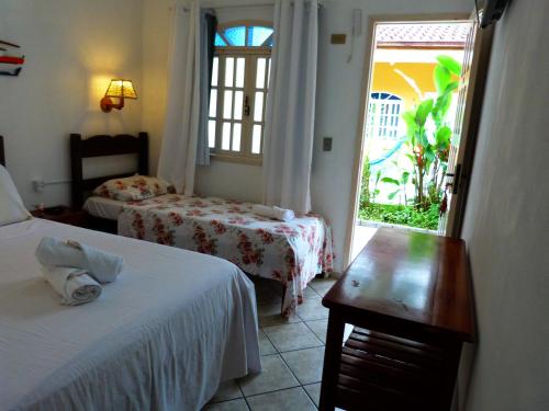 a hotel room with two beds and a window at Pousada Vila do Sonho in Paraty