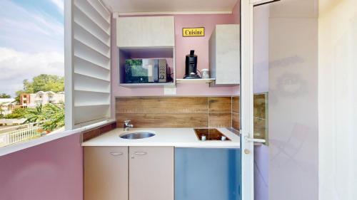 una pequeña cocina con fregadero y ventana en 150 de Grey Studio pour 2 avec SPA, Vue sur mer en La Trinité