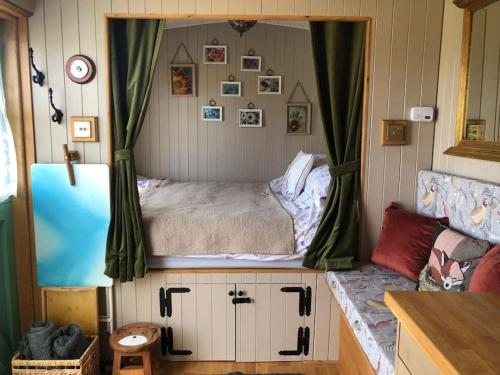 a small bedroom with a bed in a window at Shepherd’s Hut with complete privacy in Bottesford