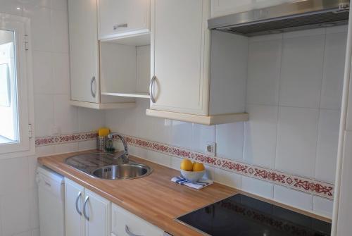 a kitchen with white cabinets and a sink at Carmen Apartamento Millón - Private roof terrace with Jacuzzi & BBQ in Nerja
