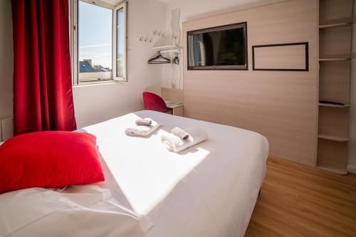ein Hotelzimmer mit einem Bett und einem TV in der Unterkunft Hôtel de la Mairie in Saint-Pol-de-Léon