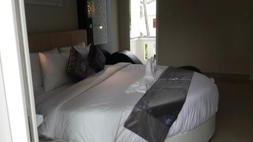 a bedroom with a bed with white sheets and pillows at Muine Sports Hotel in Mui Ne