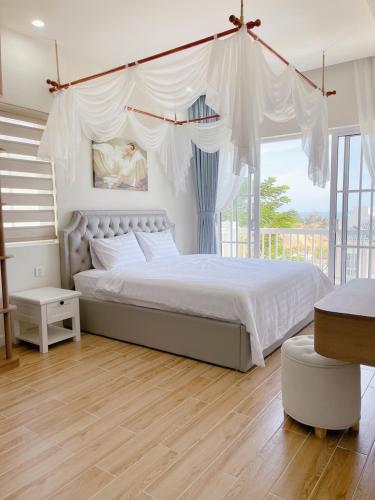 a bedroom with a large white bed with a canopy at Blue Village in Bình Tú