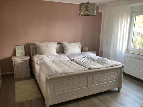 un letto con lenzuola e cuscini bianchi in una camera da letto di Schön gelegene Ferien-/Pendlerwohnung nahe Rothaarsteig mit guter Anbindung a Haiger