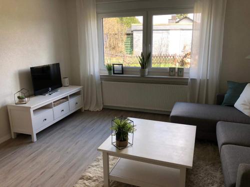a living room with a couch and a tv and a table at Schön gelegene Ferien-/Pendlerwohnung nahe Rothaarsteig mit guter Anbindung in Haiger