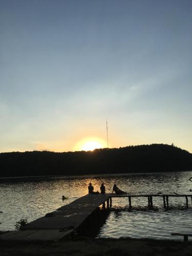 two people sitting on a dock in the water at sunset at Słoneczne Wzgórze in Łagów