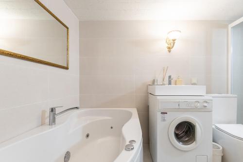 a bathroom with a white tub and a washing machine at In the heart of the Old Town VIP Apartment in Klaipėda