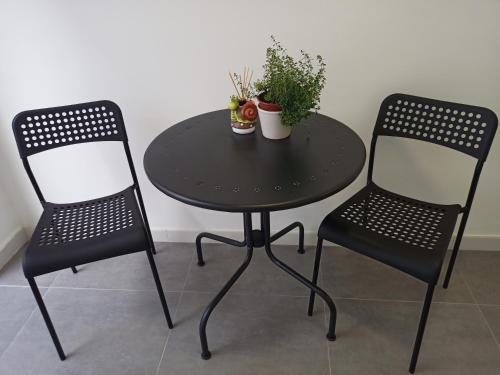 dos sillas y una mesa negra con plantas. en La Casa de Ángela en Sevilla