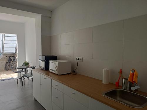uma cozinha com um lavatório e um micro-ondas no balcão em La Casa de Ángela em Sevilha