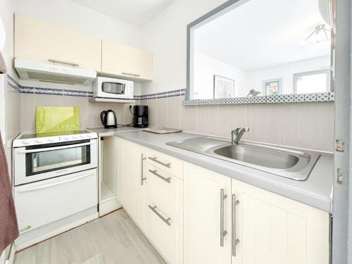 a kitchen with white cabinets and a sink at Agréable appartement proche de Port Olonna - 4 pers in Les Sables-dʼOlonne
