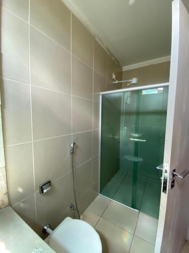 a bathroom with a toilet and a glass shower at Pousada Aliany Lôbo in Pirenópolis