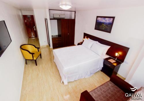 Qallwa Pucallpa في بوكالبا: غرفة نوم بسرير ابيض وكرسي اصفر