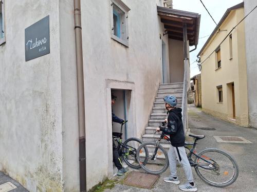 un hombre parado fuera de un edificio con dos bicicletas en Lukova hiša- Luka's house, en Vipava
