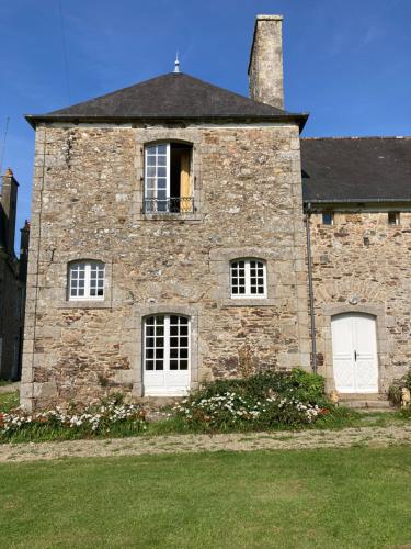 una antigua casa de piedra con dos puertas blancas y una ventana en Domaine de la Motte-Basse en Le Gouray