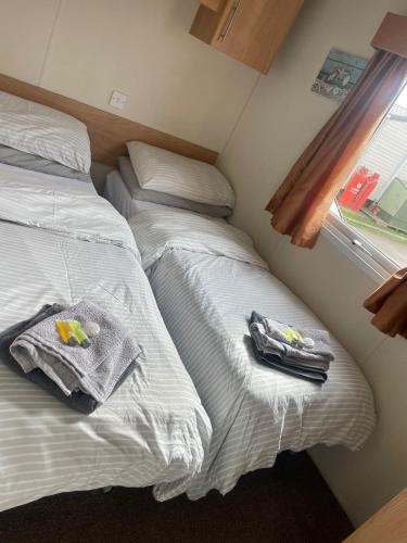 two beds in a room with towels and a window at Alberta Holiday Park, HC13 in Seasalter