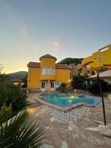 a villa with a swimming pool in front of a house at Yellow Villa With A Sea View in Budva