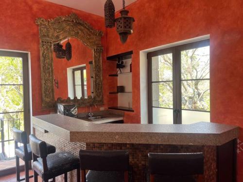 cocina con paredes rojas y espejo grande en Paseo del Obispo Apartamento A3, en Antigua Guatemala