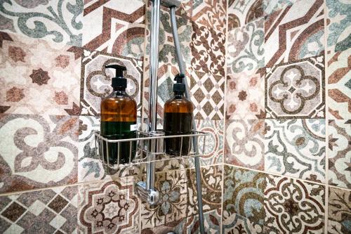 duas garrafas de vinho num suporte numa parede de azulejos em CsendÉlet Vendégház 