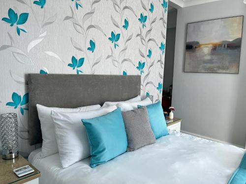 a bedroom with a bed with blue pillows at Bentley Lodge in Torquay