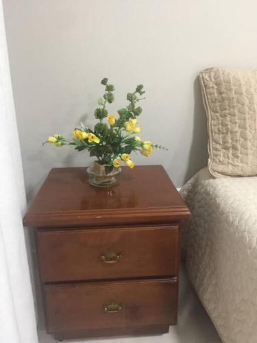 a vase of yellow flowers on a wooden table next to a bed at Ideal Apartaestudio con Piscina!!! in Dosquebradas
