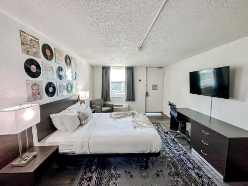 a hotel room with a bed and a desk and a television at Sleepover Nashville Studio Apartments in Nashville